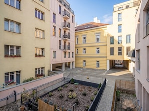 Ein Innenhof mit einem zentralen Garten, umgeben von mehrstöckigen Gebäuden mit Balkonen und Fenstern.