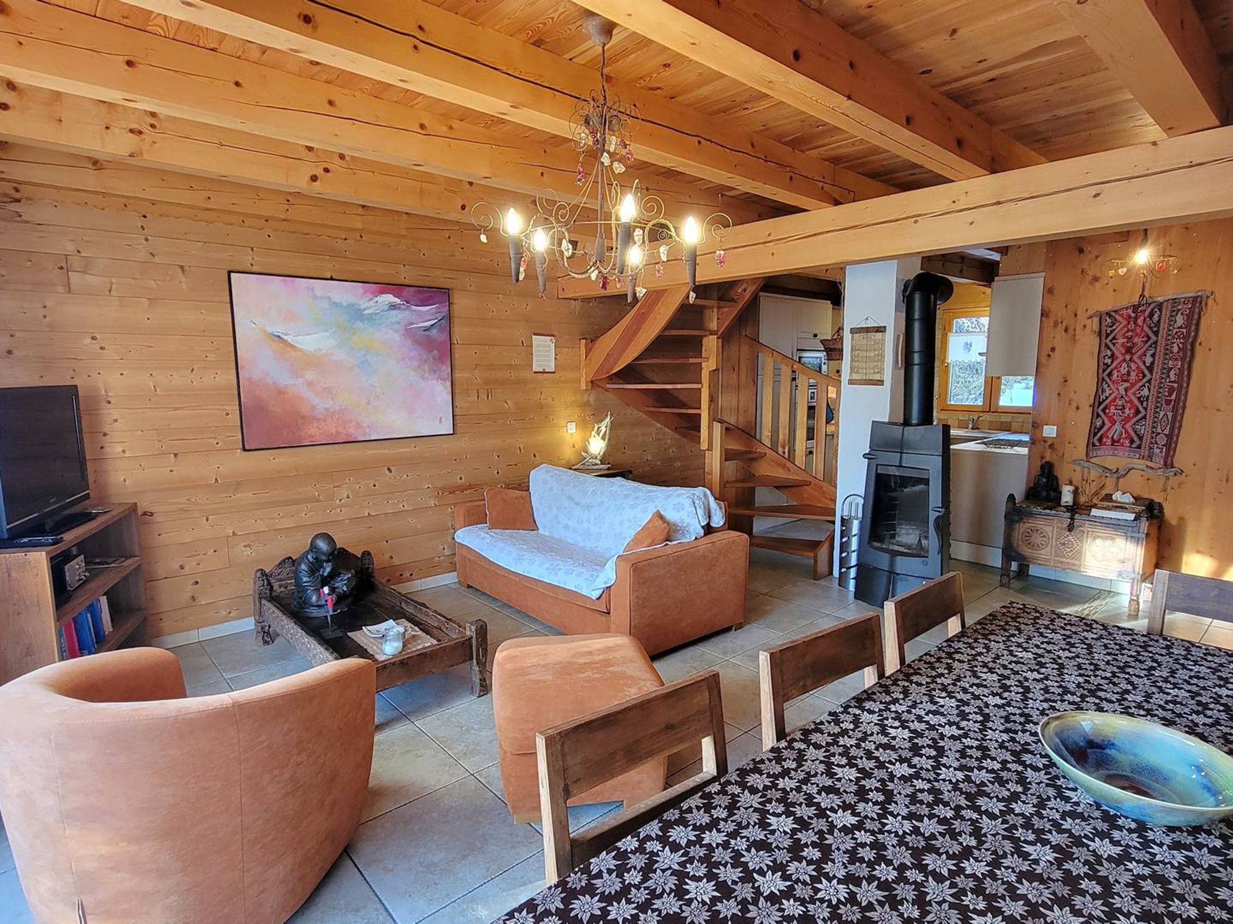 Un interior de madera acogedor con un sofá, sillas, una chimenea y una escalera.