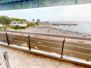 A balcony with a view of a beach, a parking area, and a road. - Apartment with AC and parking facing the sea (Roquebrune-Cap-Martin)