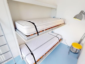 Ein Stockbett mit einer Leiter, einem Schreibtisch und einem Stuhl in einem Raum mit blauem Boden.