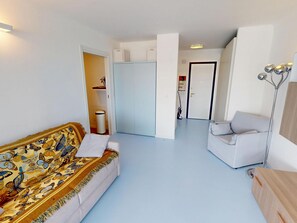 A living room with a sofa, a chair, and a floor lamp. There is a door leading to another room. - Apartment with AC and parking facing the sea (Roquebrune-Cap-Martin)