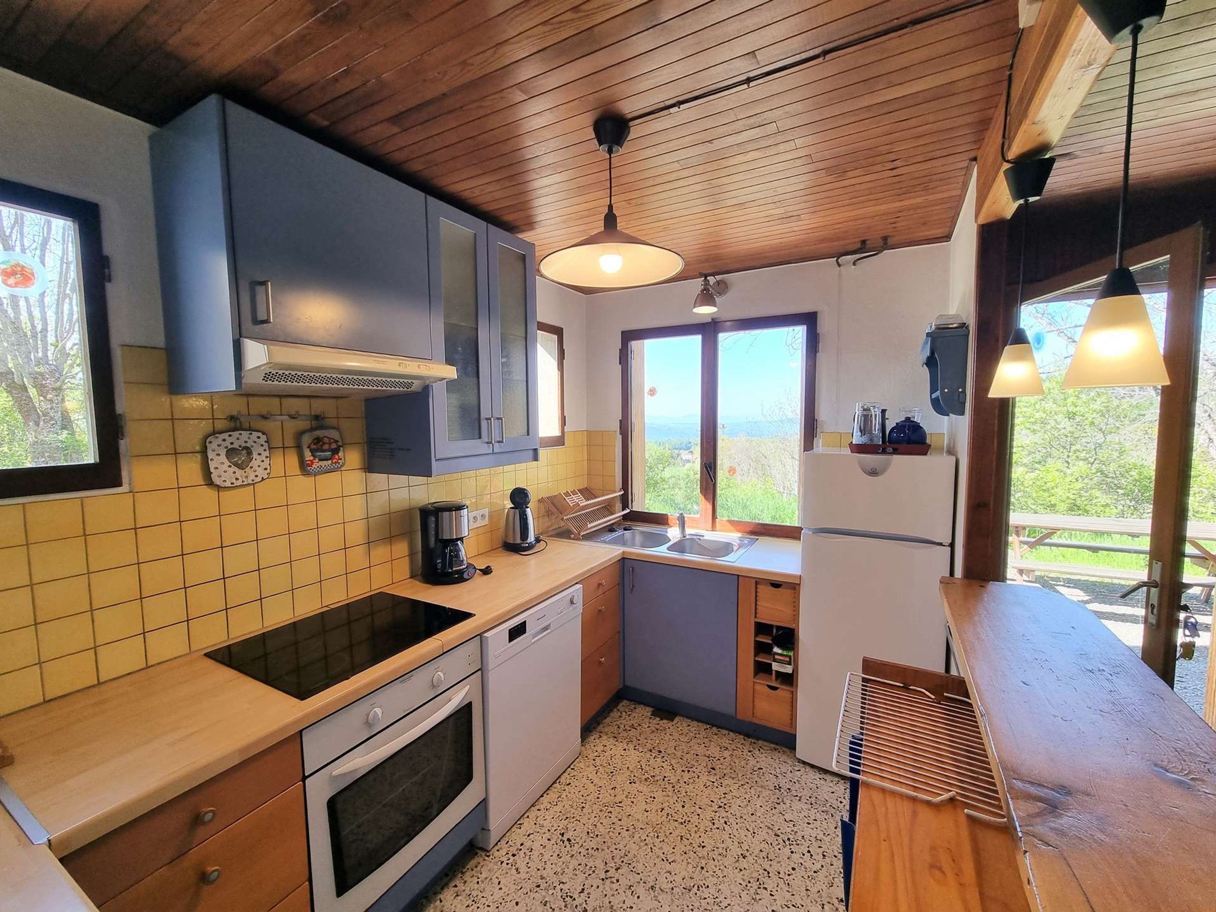 Cocina compacta con horno empotrado, cafetera y lavamanos.