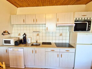 A compact kitchen with white cabinets, a microwave, a toaster, a coffee maker, and a dishwasher.