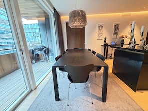 A modern dining area with a long table, chairs, and a hanging light fixture. - Luxary apartment in downtown Reykjavik (Reykjavík)