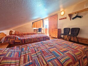 A dorm-style room with two beds, a desk, a chair, and a wardrobe.