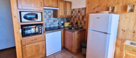 A compact kitchen with wooden cabinets, a microwave, a dishwasher, and a refrigerator.