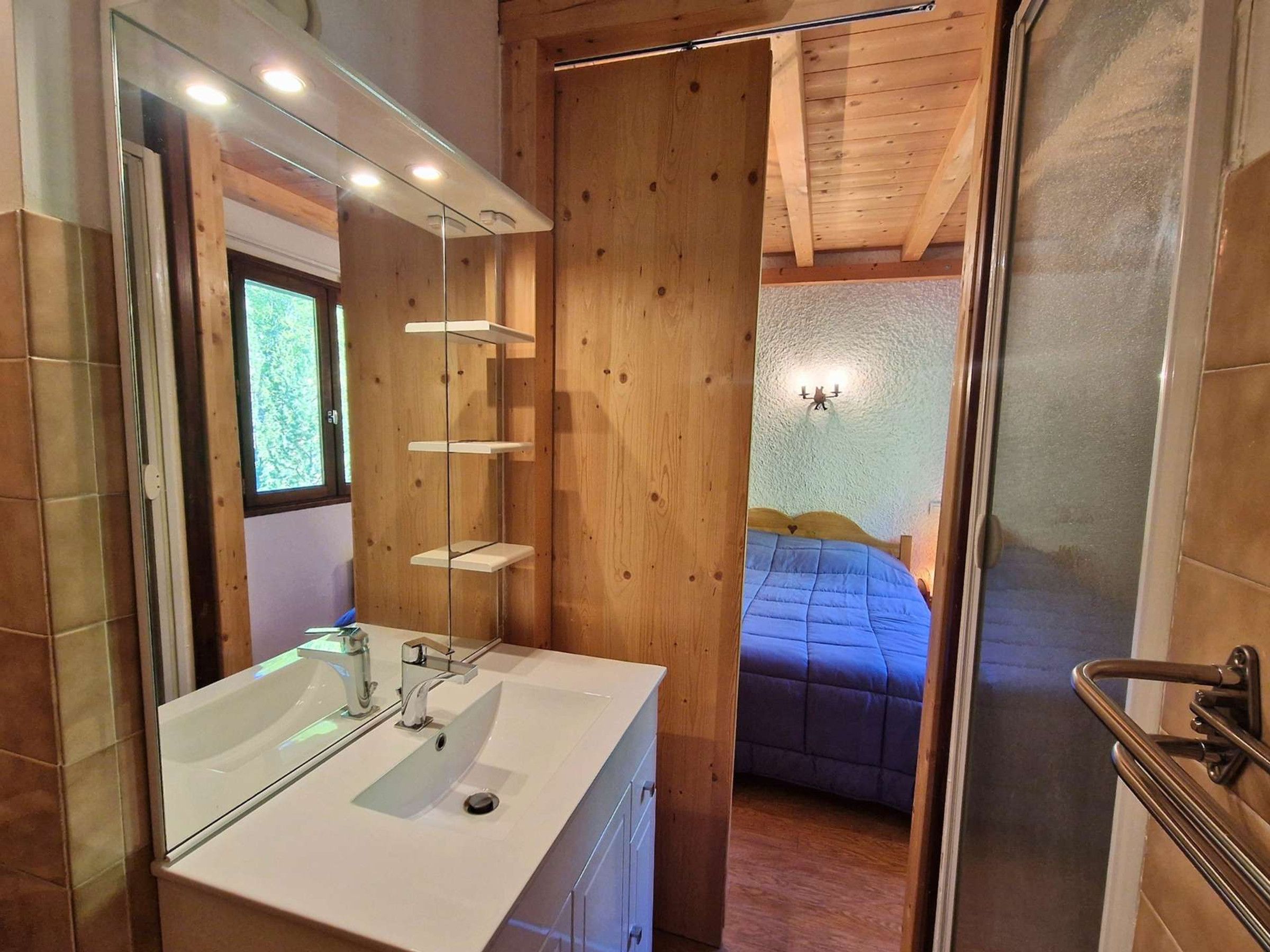 Une salle de bain avec un miroir, un lavabo et un lambris en bois.