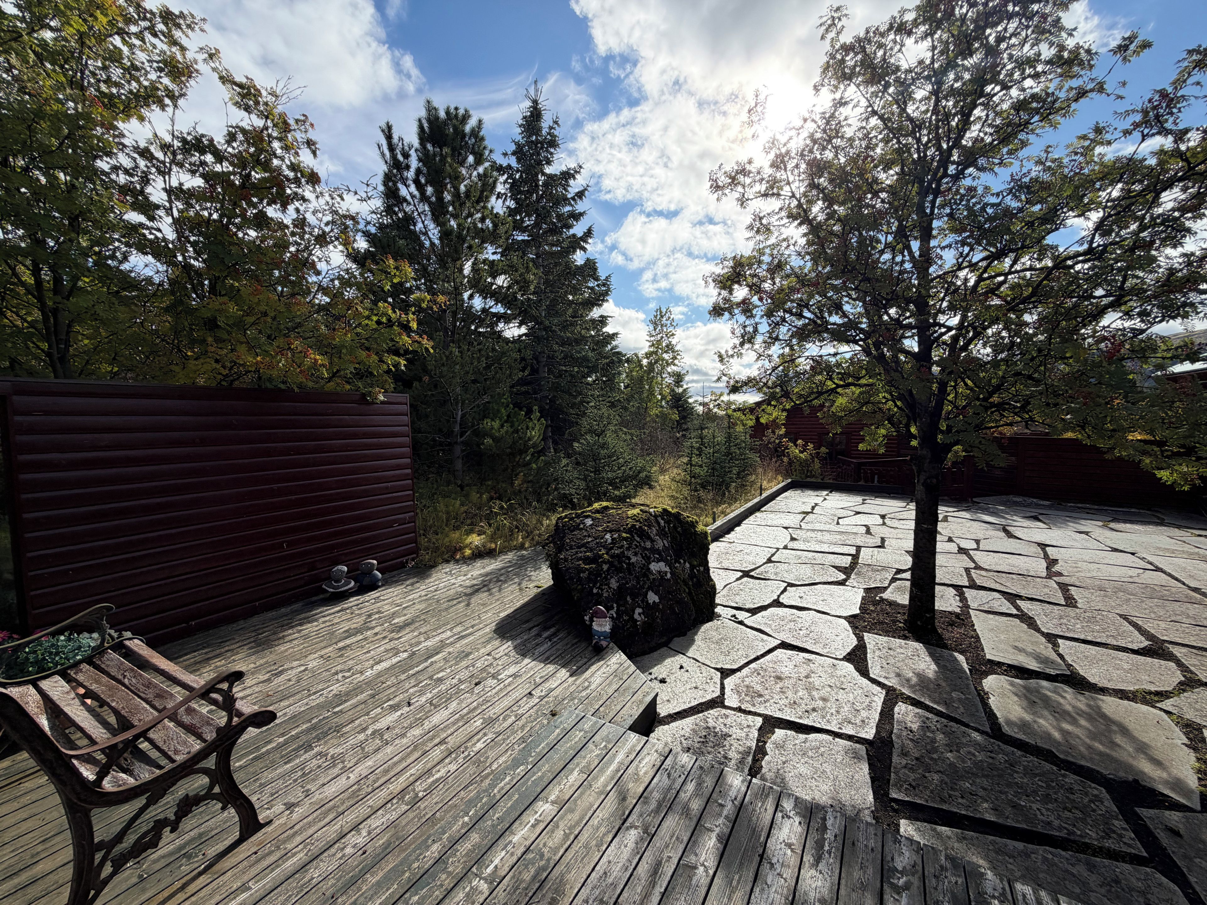 A wooden deck with a bench and a stone pathway.