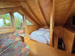 Ein Schlafzimmer einer Holzhütte mit einem Bett, einem Nachttisch, einer Lampe und einem Fernseher.