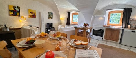 A dining area with a table set for two, a book, and a fruit plate.