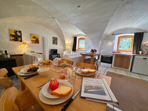 A dining area with a table set for two, a book, and a fruit plate. - Charming apartment in Vars - 6 guests (Vars)