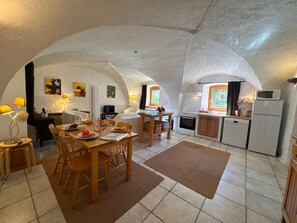 A cozy kitchen with a dining area, white walls, and a tiled floor. - Charming apartment in Vars - 6 guests (Vars)