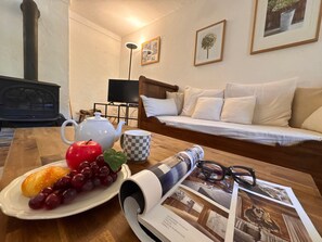 A wooden table with a teapot, a plate of fruit, a checkered mug, and a magazine with photographs. - Family apartment valley view - 10 guests (Vars)