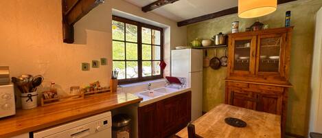 A kitchen with a wooden countertop, a sink, a dishwasher, and a window with a view of greenery.