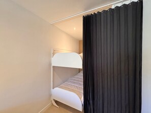 A single bunk bed room with a white headboard, a black curtain, and a light-colored floor. - Apartment in the heart of Vars - 4 guests (Vars)
