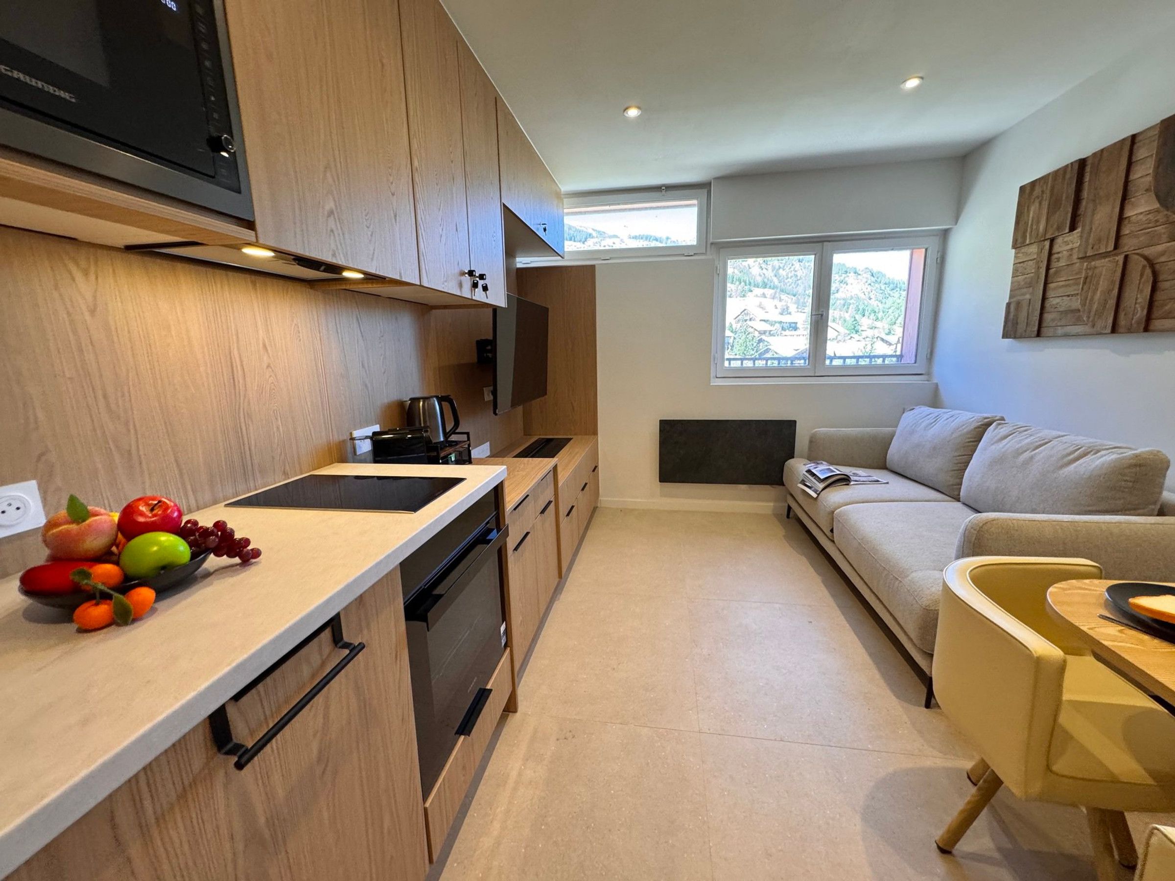 A modern kitchen with wooden cabinets, a built-in oven, and a fruit bowl on the counter.