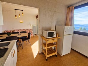 Une cuisine compacte équipée d’un four à micro-ondes, d’un réfrigérateur et d’un coin repas avec une table et des chaises.