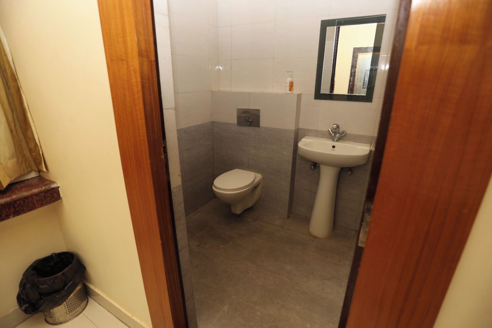 A bathroom with a toilet, sink, and mirror.
