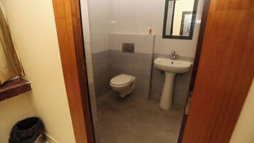 A bathroom with a toilet, sink, and mirror.