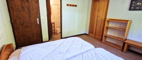 Une pièce comprenant un lit, une armoire en bois et une petite étagère en bois.