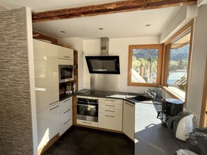 A modern kitchen with a built-in oven, microwave, and a large window providing a view of the outdoors. - Spacious chalet for 8 guests - 3 bedrooms (Valloire)