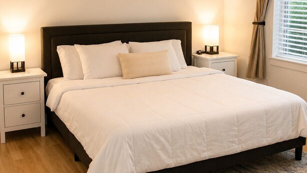 Une chambre à coucher avec un lit, des tables de chevet, un tapis et une fenêtre avec des rideaux.