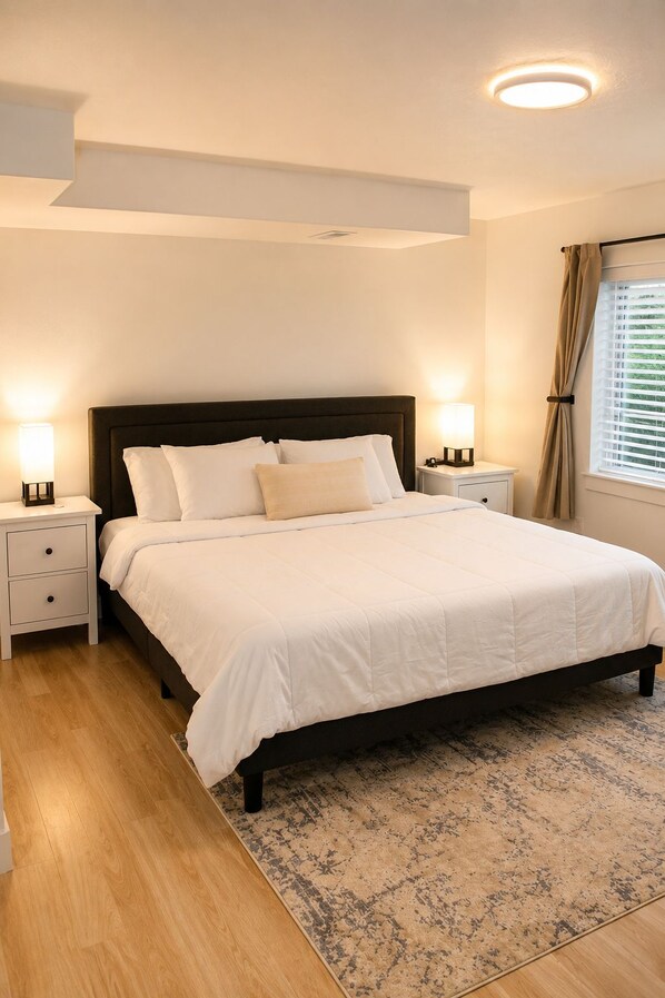 A bedroom with a bed, nightstands, a rug, and a window with curtains.