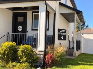 A guest entrance with a black door, a welcome sign, and a directional arrow sign.
