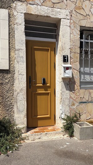 A stone building with a wooden door, a mailbox, and a window with a metal grille. - Kaki Suite Apartment, in the heart of the "Venice of Provence." (Martigues)