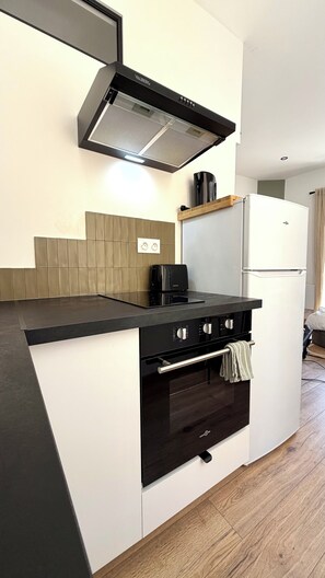 A modern kitchen with a built-in stove, oven, and a black range hood. - Kaki Suite Apartment, in the heart of the "Venice of Provence." (Martigues)