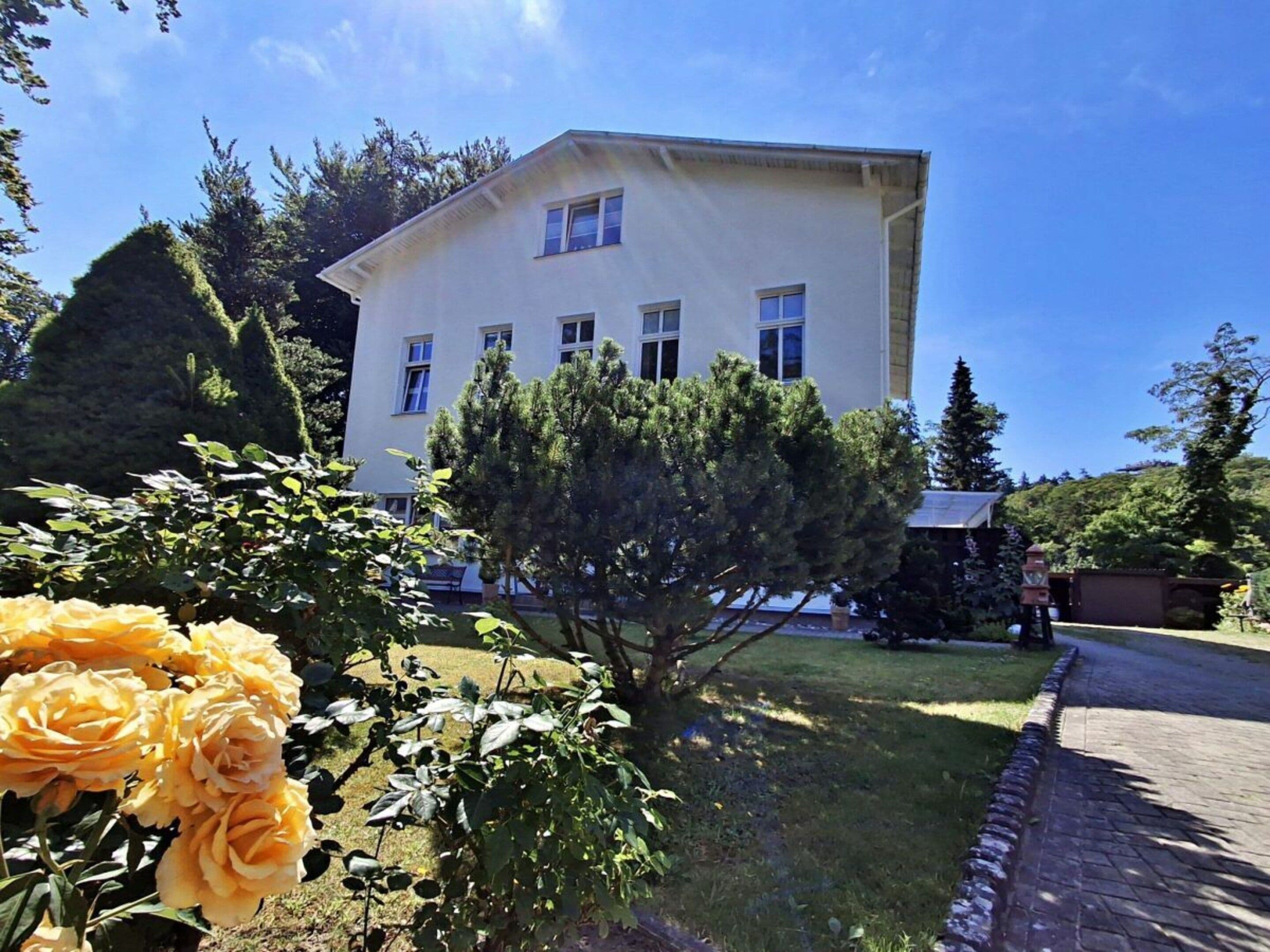 A two-story building with a flat roof, surrounded by a well-maintained lawn and a variety of trees.