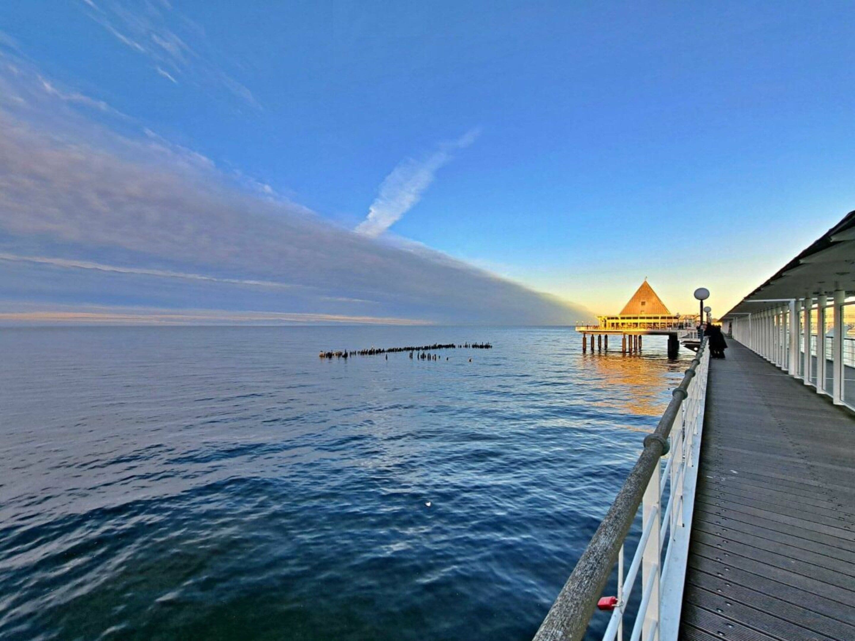 A wooden pier extending into calm waters with a building at the end.