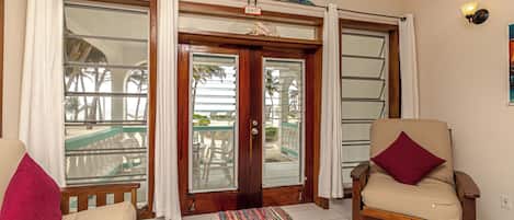 Une pièce avec une porte en bois, un banc, une chaise et une vue sur l’extérieur, visible à travers la porte.