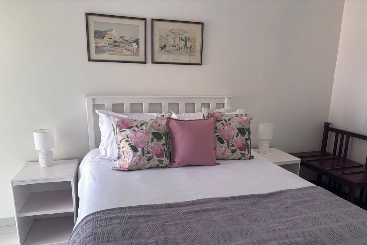 A bedroom with a bed, nightstands, a headboard, and two framed pictures on the wall.