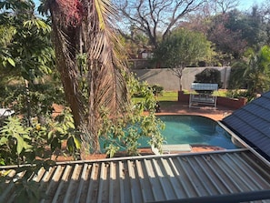 Una piscina con jardín circundante, una pérgola y vista a zona residencial.