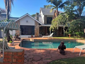 A residential property with a swimming pool, outdoor seating, and a covered patio area. - On Guest Av (Harare)