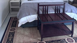 A bedroom with a bed, two nightstands, a wooden chair, a ceiling fan, and decorative plates on the wall. - On Guest Av (Harare)