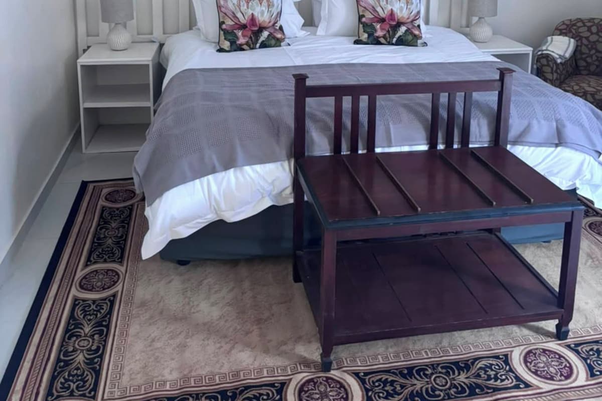 A bedroom with a bed, two nightstands, a wooden chair, a ceiling fan, and decorative plates on the wall.