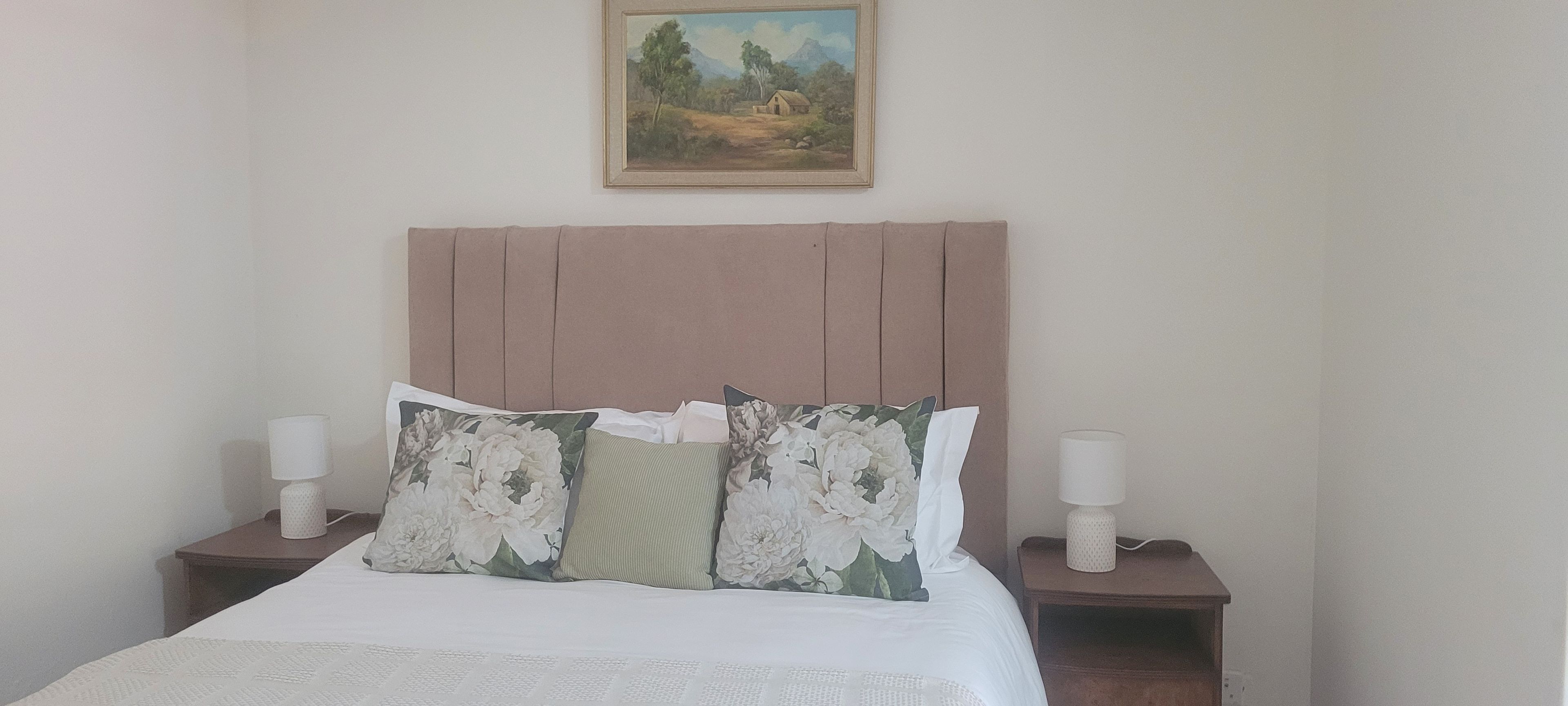 Una cama con almohadas estampadas, un cabecero y lámparas de noche.