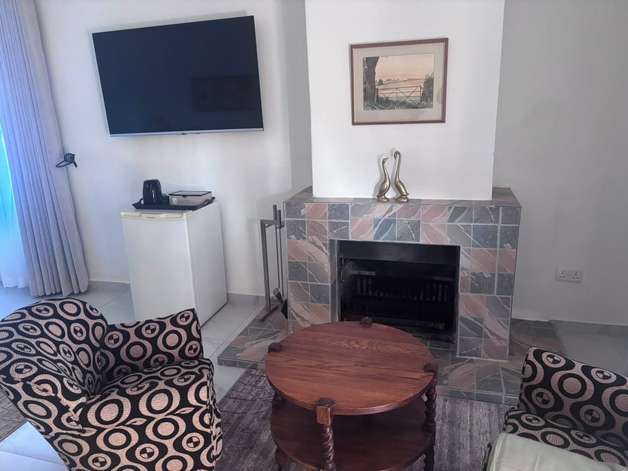 Ein Wohnzimmer mit Kamin, einem an der Wand montierten Fernseher und gestreiften Sofas.