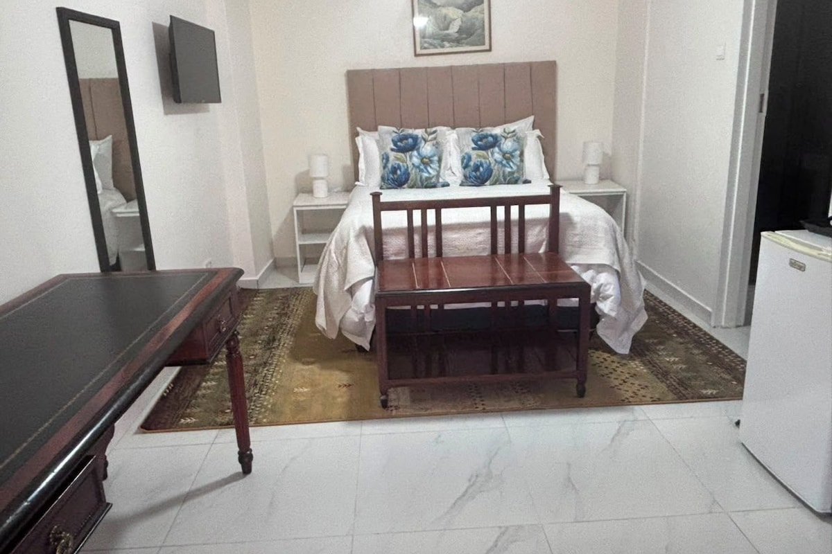 A bedroom with a bed, bedside tables, a mirror, a dresser, and a television.