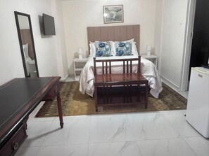 Un dormitorio con cama, mesitas de noche, cómoda y espejo.
