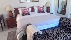 A hotel room with a bed, two bedside tables with lamps, a patterned sofa, and a large mirror on the wall. - On Guest Av (Harare)