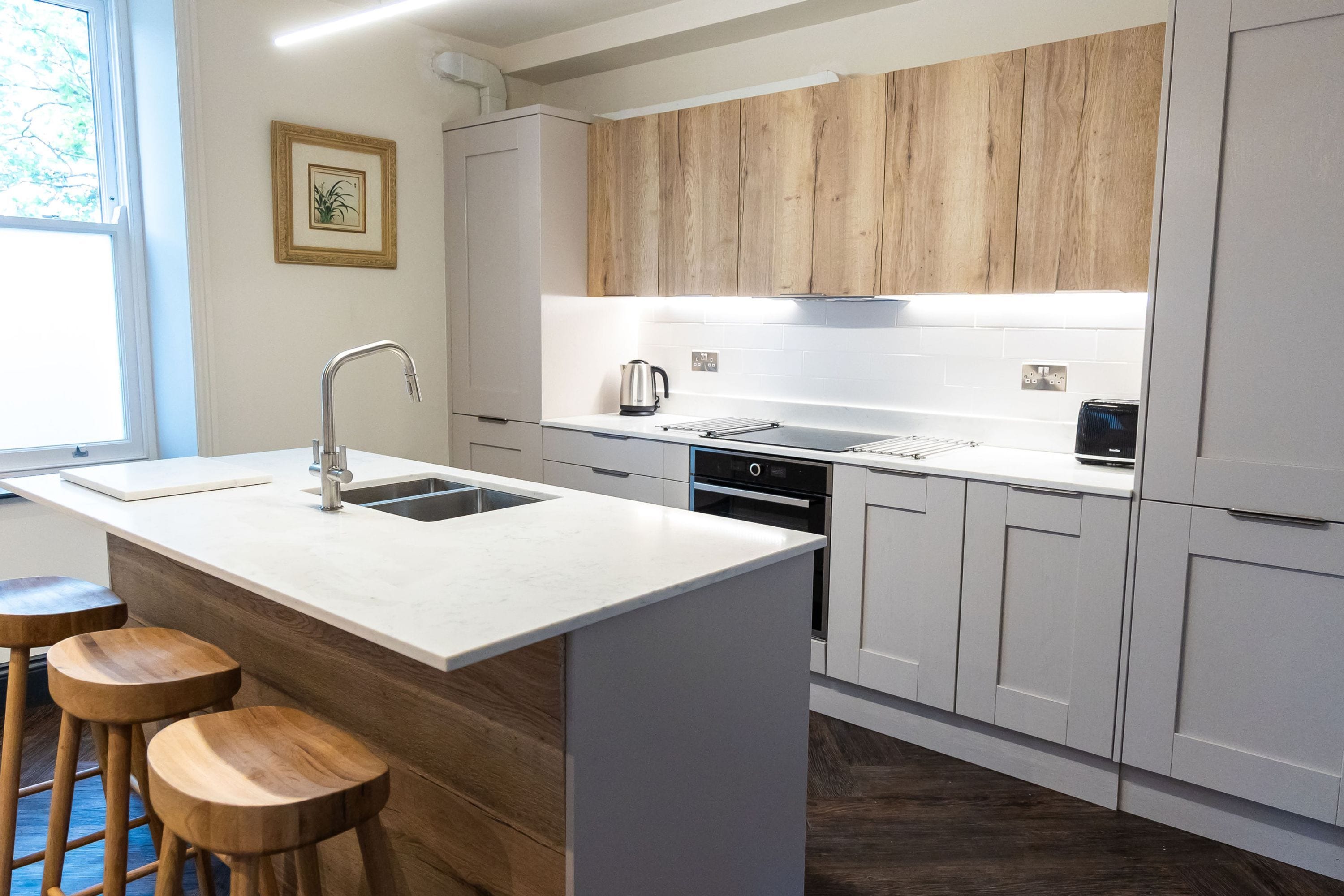 Une cuisine moderne dotée d’un îlot central, de tabourets de bar et de meubles de rangement en bois.