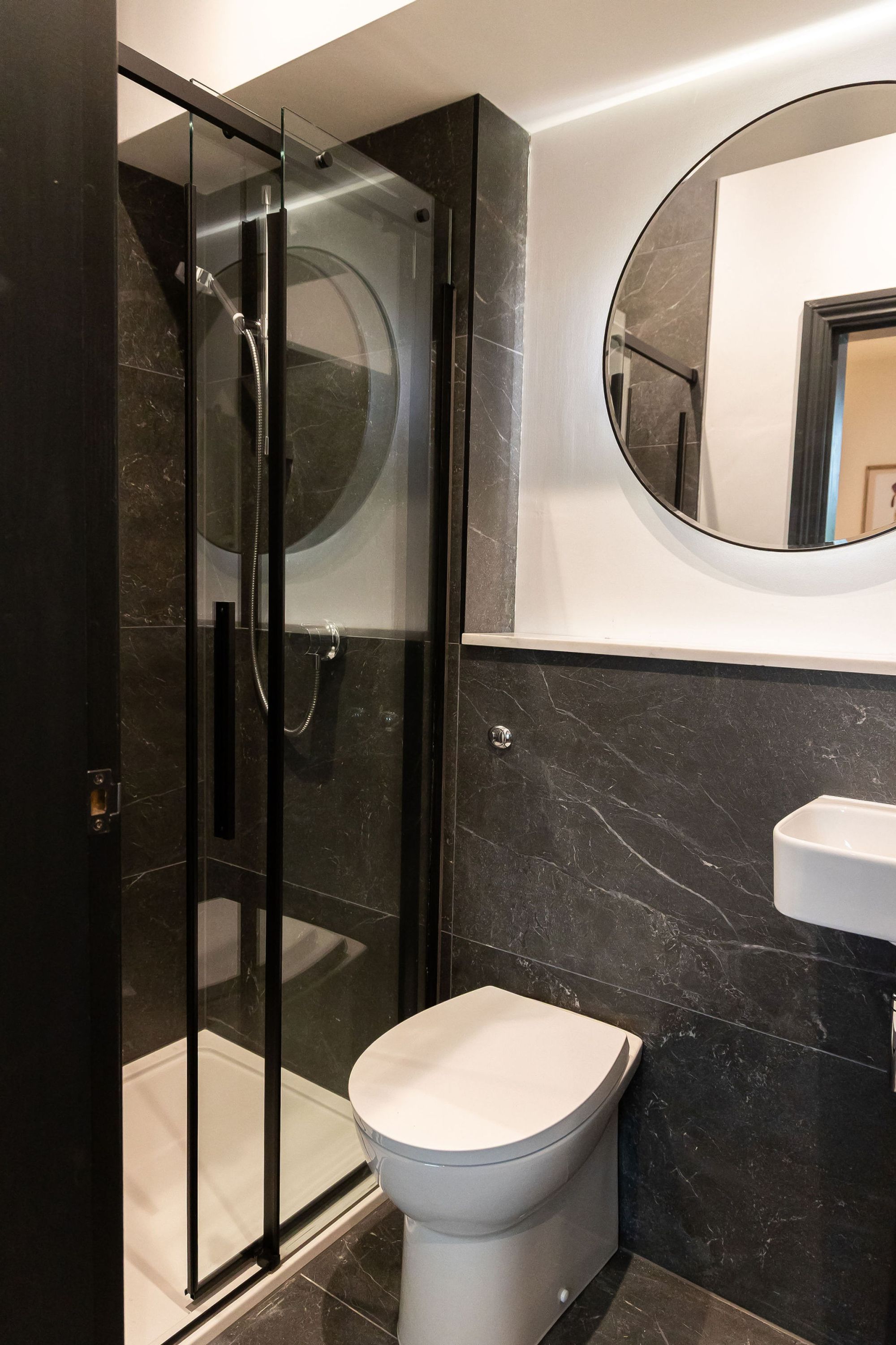 Un bagno moderno con doccia vetrata, un water e un lavandino.