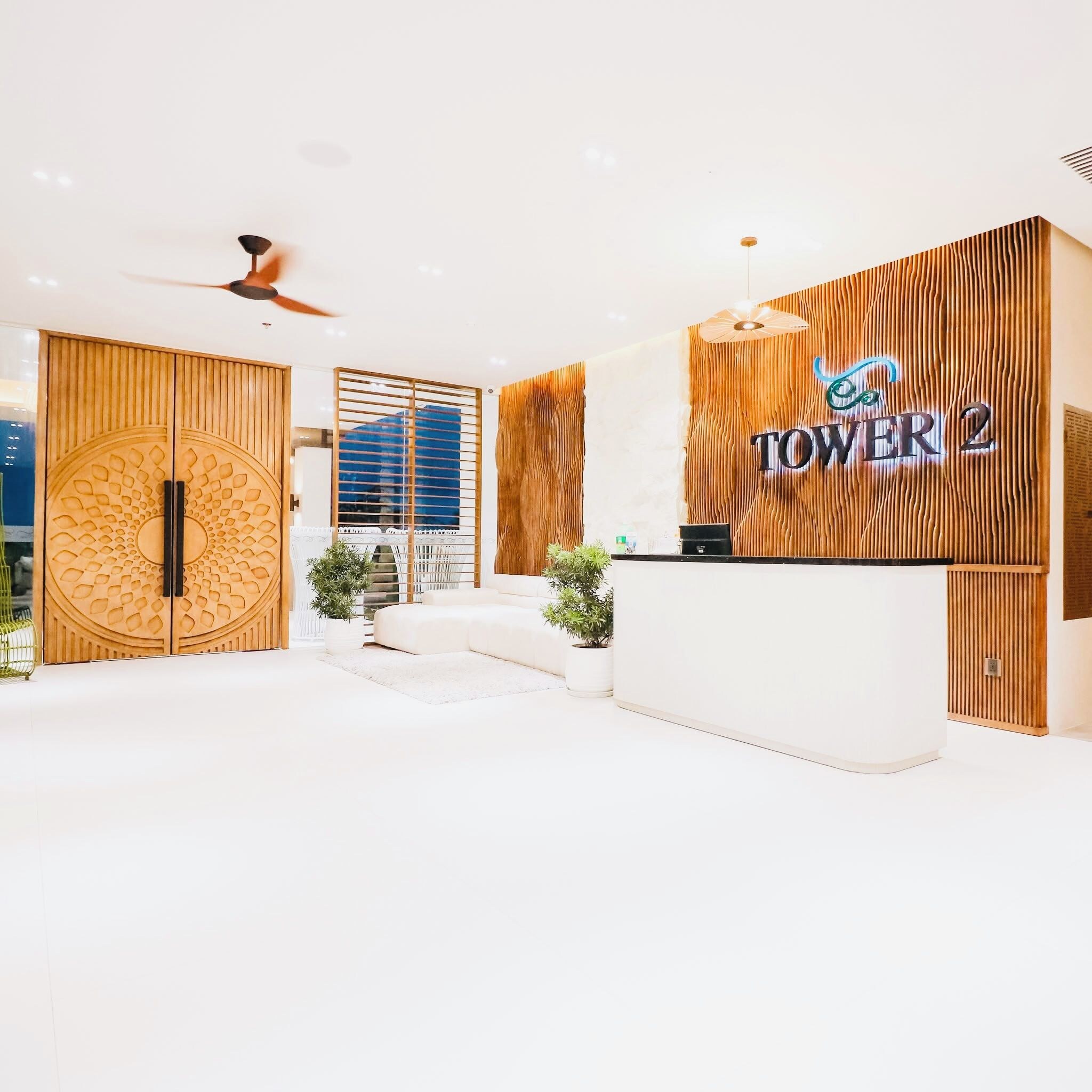 Un área de recepción de diseño moderno, con mostrador de recepción, pared de madera con listones verticales y ventilador de techo.