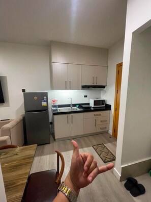 Una cocina funcional equipada con refrigerador, microondas y armarios.