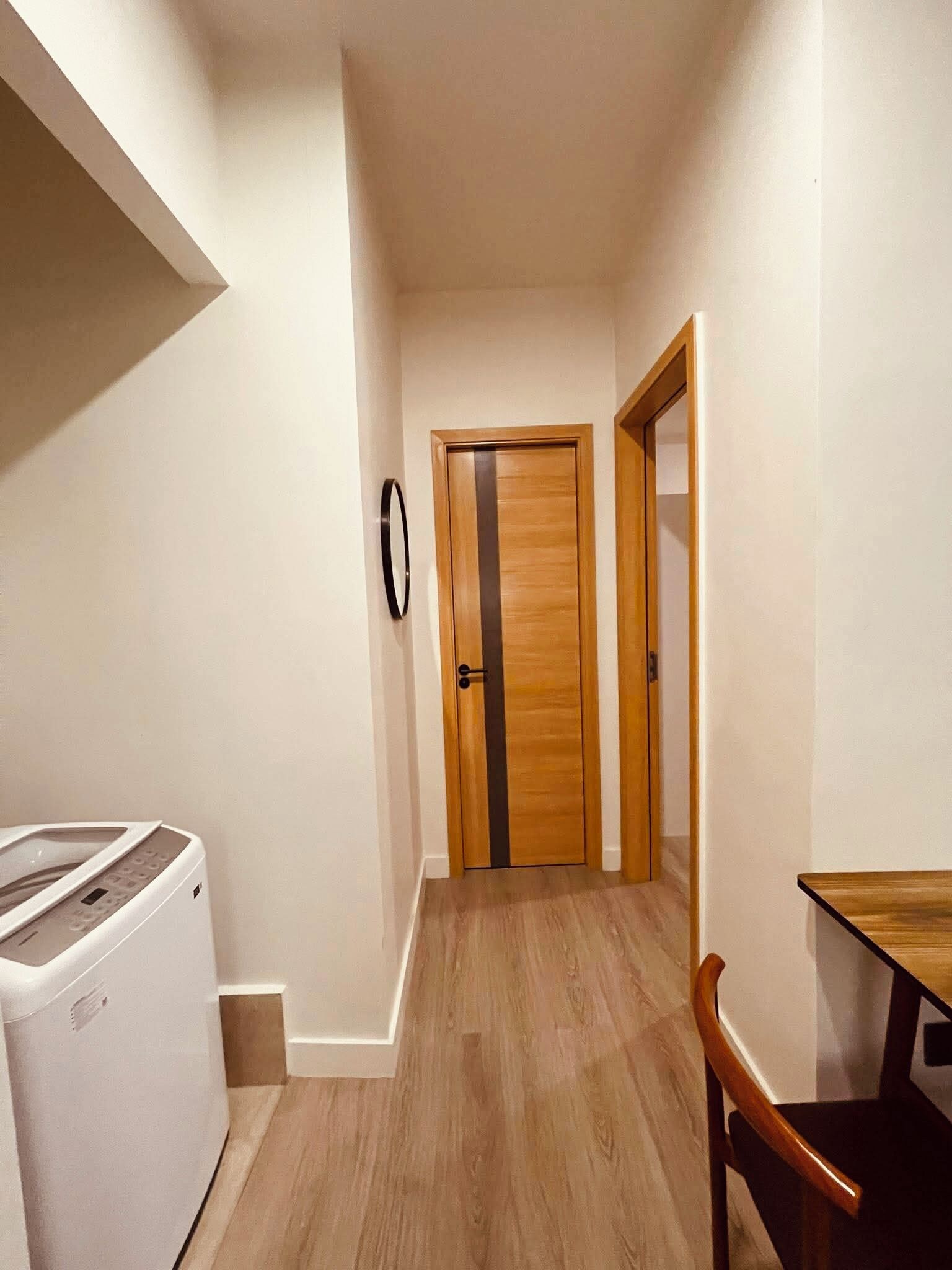 A hallway with a wooden door, a washing machine, and a dining table.