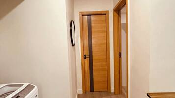 A hallway with a wooden door, a washing machine, and a dining table.