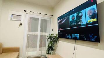 A living room with a flat-screen TV mounted on the wall displaying multiple movie options.